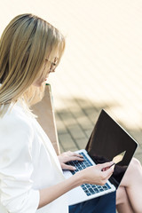 young blonde woman holding credit card and using laptop