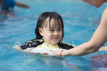 Fototapeta na wymiar Asian Chinese family playing in swimming pool
