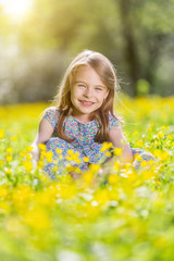 Naklejka na ściany i meble Happy little girl on spring blooming meadow