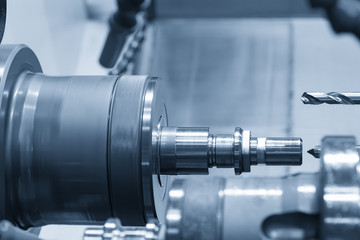Fototapeta premium The CNC lathe machine or turning machine drilling the hole at the steel shaft part.Modern manufacturing process.