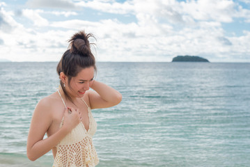 Beautiful young woman in sexy bikini standing at sea beach