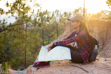 Obraz premium Turysta żeński trzymając w ręku mapę, siedząc w pięknej przyrody na górze.