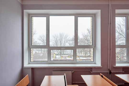 Closeup of desk and chairs in light classroom with big window