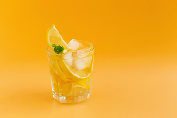 Detox Water with lemon in a glass on an orange background