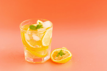 Detox Water with lemon in a glass on an orange background