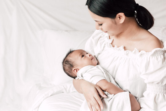 Mother holding baby in her arms in a white bedroom.Love of family concept
