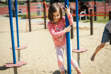 Fototapeta na wymiar little smiling girl is playing on the playground on a summer day