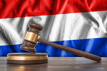 Wooden gavel and flag of Netherlands on background - law concept