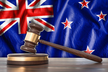 Wooden gavel and flag of New Zealand on background - law concept