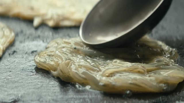 Extreme close up raw whitebait placed onto hot stove