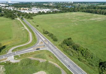 Aerial view of the turn-off of a ring road with the houses of the dominion in the background