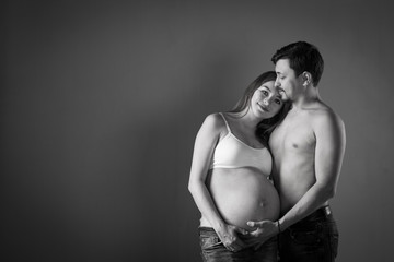 Husband and pregnant wife on gray background