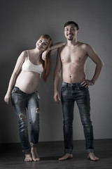 Husband and pregnant wife on gray background