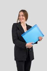 young successful woman in a strict dark suit with a blue folder in hands looking aside and smiling