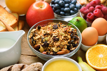 Healthy breakfast ingredients, food frame. Granola, egg, nuts, fruits, berries, toast, milk, yogurt, orange juice, cheese, banana, apple on wooden rustic background, top view, copy space.
