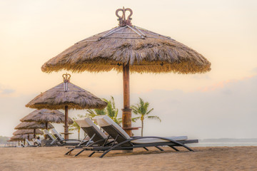 Palm trees on white sandy beach, two sunbed and parasol. View of nice tropical beach.