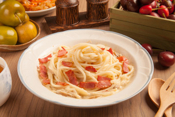 Spaghetti with bacon and cream sauce on plate.