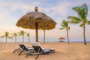 Palm trees on white sandy beach, two sunbed and parasol. View of nice tropical beach.