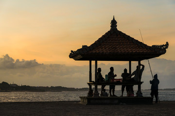 Sunset on the beach, silhouette hut and a few people