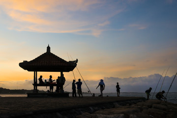 Sunset on the beach, silhouette hut and a few people