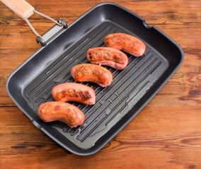 Grilled sausages on rectangular grill pan on rustic table