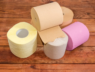 Rolls of various toilet paper different colors on wooden surface