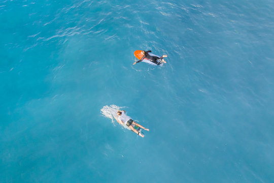 Two surfers on a surfboards in the water, top view