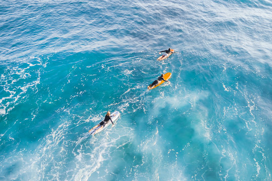Three surfers in the ocean, top view