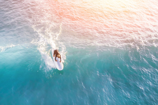 Surfer in the ocean in the sunlight, top view
