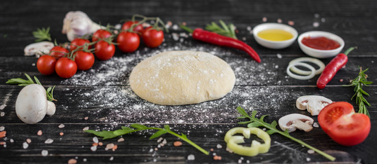 Preparation of the dough and vegetables to production of pizza. Ingredients for production of pizza on a wooden background
