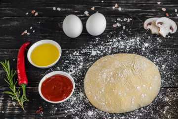 Preparation of the dough and vegetables to production of pizza. Ingredients for production of pizza on a wooden background