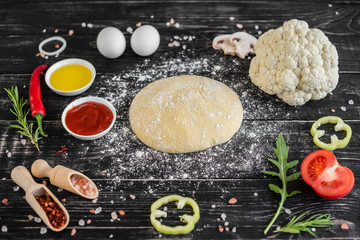 Preparation of the dough and vegetables to production of pizza. Ingredients for production of pizza on a wooden background