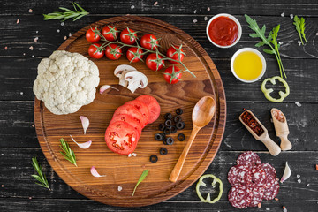 Preparation of the dough and vegetables to production of pizza. Ingredients for production of pizza on a wooden background