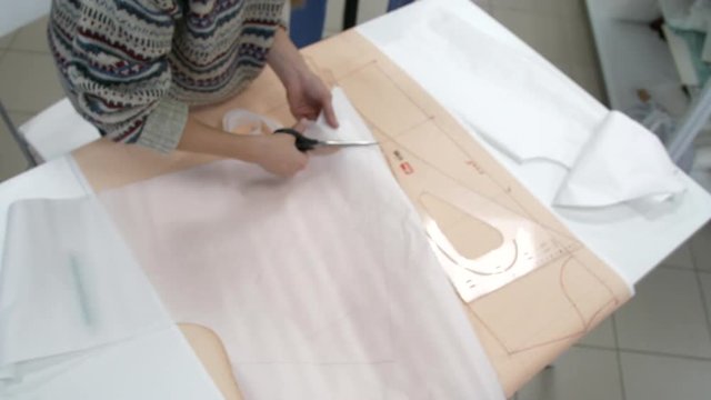 Girl cuts scissors cloth on a pattern