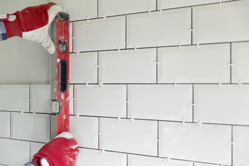 Process of tiling the tiles in the kitchen. Contractor measuring level with construction level on...