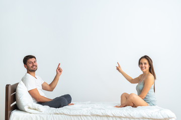 The happy couple on the bed gesturing on the white background