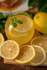 Lemon juice with honey on wooden table,  lemons and sage leaves