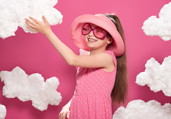 fashionable girl posing on a pink background with clouds, pink dress and hat