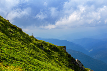 Fototapeta na wymiar green mount slope on a cloudy sky background
