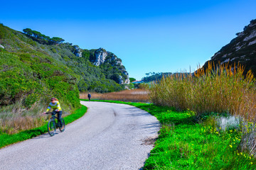 The trail, the pedestrian, car-free zone in the valley of the Alcabrichel River, surrounded by evergreen trees on steep hills. People walking along the road. Landscape near Vimeiro in Portugal.