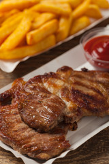 Grilled pork neck served on paper trays.