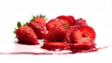 Freshly washed ripe Strawberries dripping in water on white background at eye level camera anlgle.