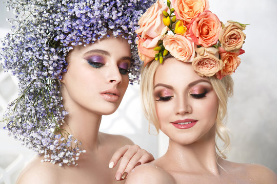 Fashion beauty portrait of two beautiful girls in flower wreaths.