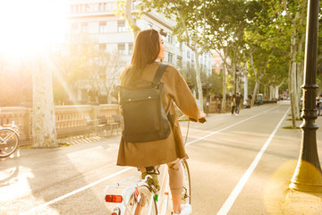 Back view image of young lady on bicycle on the street.