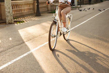 Cropped photo of young lady on bicycle on the street.