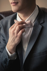 a man in a suit suits his hand with a bow tie
