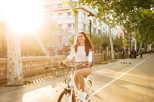 Pretty woman outdoors with bicycle on the street in park.