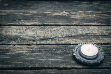 Obraz na płótnie Canvas Burning candle on aged wooden table background with copy space.