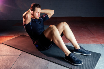 Obraz premium young and beautiful sportsman male doing exercises for muscles of the body in the gym. concept of a healthy lifestyle and bodybuilding