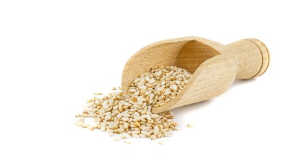 Sesame seeds in a wooden scoop on a white background with copy space for your text